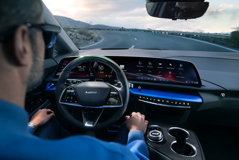 Front View of the 2026 OPTIQ-V Driving Through the Dusk Utilizing its Headlights | Sport Cadillac in Silver Spring MD