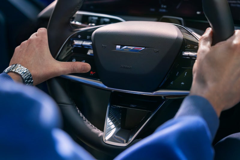 Close-up of a Man About to Press the V-Button on the 2026 OPTIQ-V Steering Wheel | Sport Cadillac in Silver Spring MD