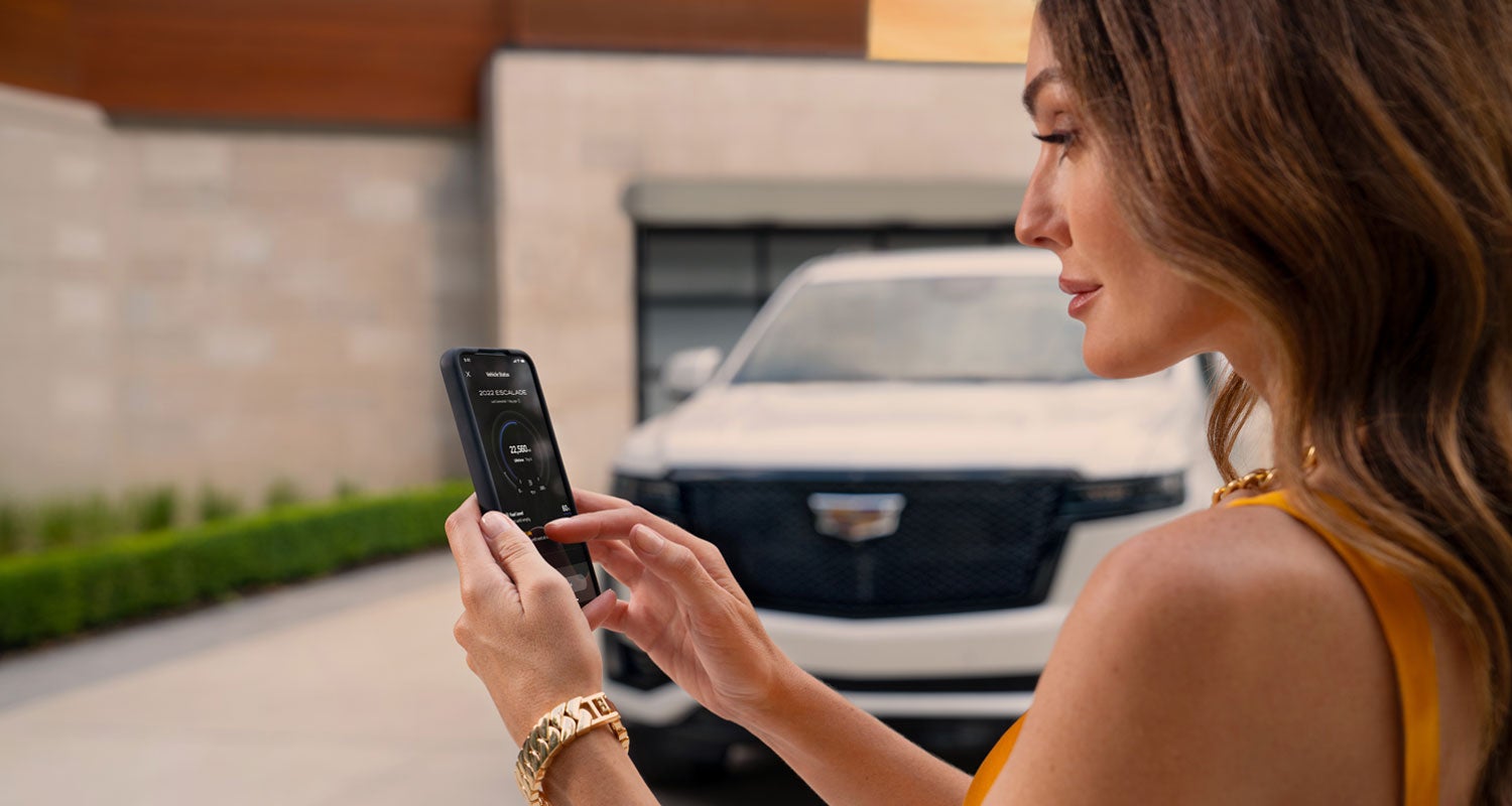 lady checking her mobile with a Cadillac vehicle background | Sport Cadillac in Silver Spring MD